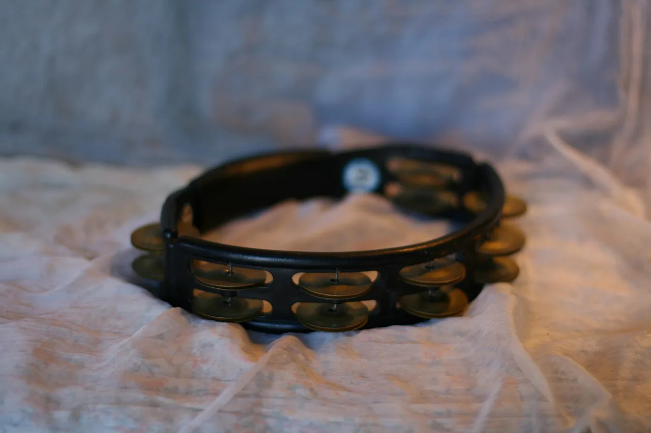 A tambourine resting on a surface, jingles catching the light.