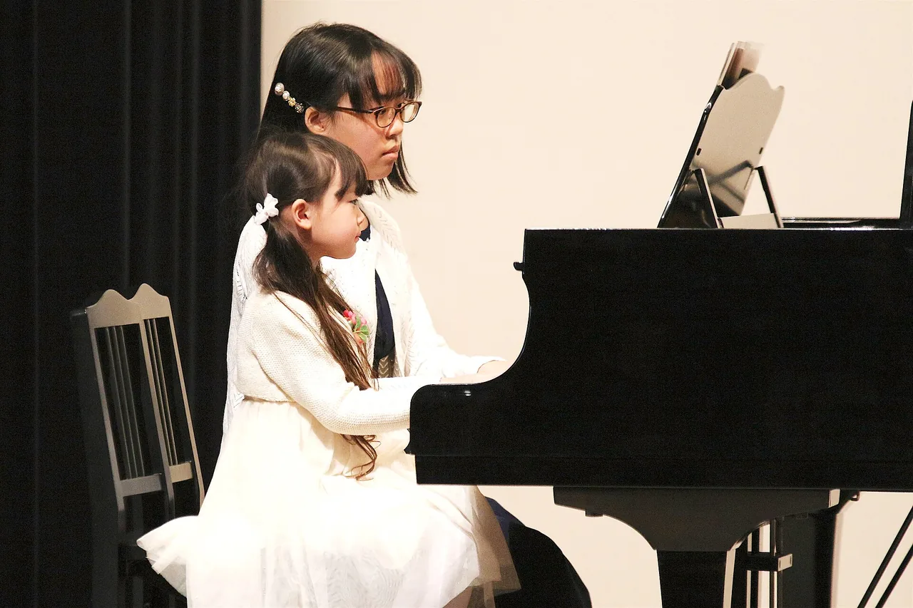 A girl plays a grand piano at a recital.